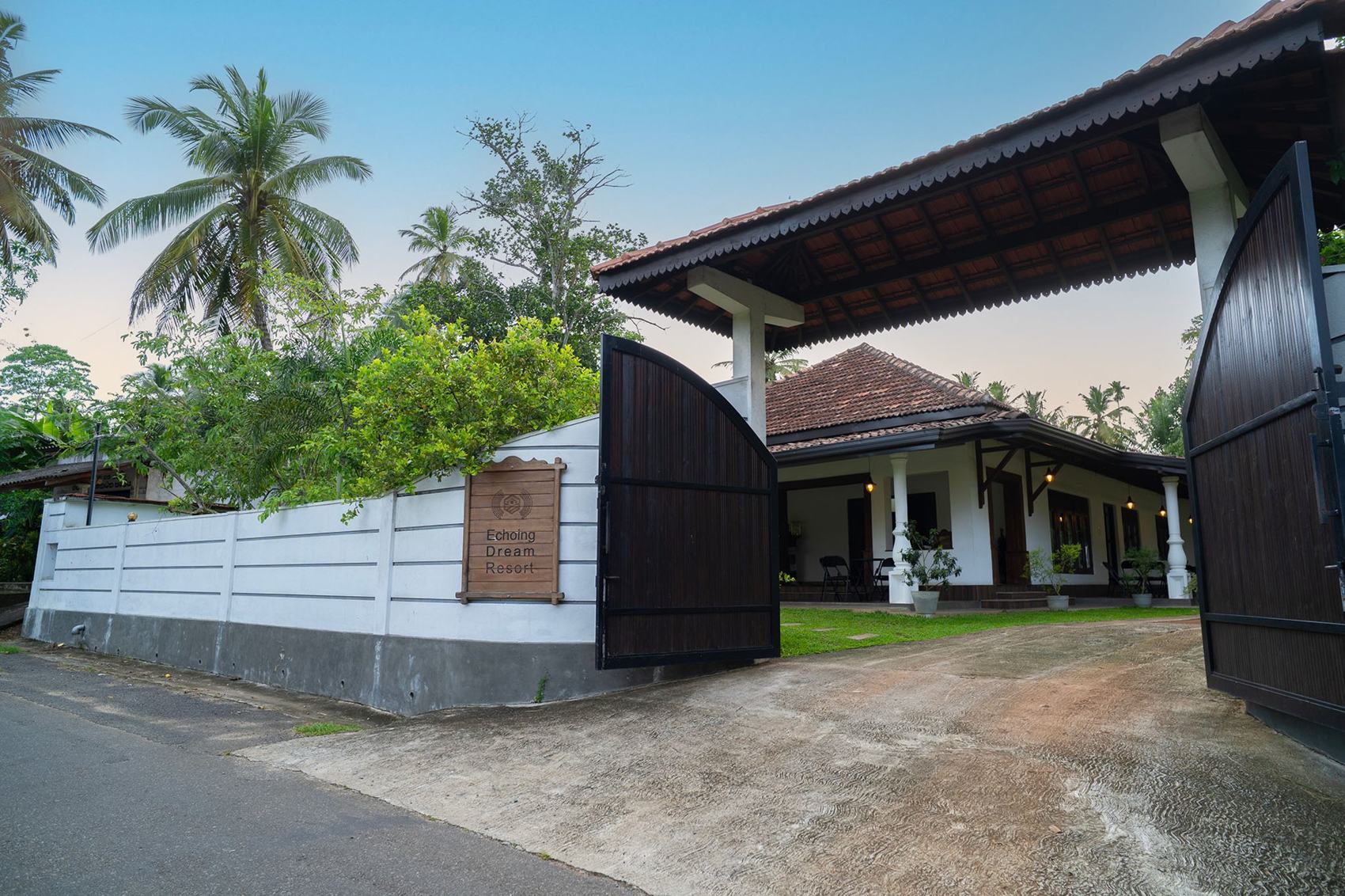 The entrance gate of Echoing Dream Resort at dusk, with its carved wooden name sign