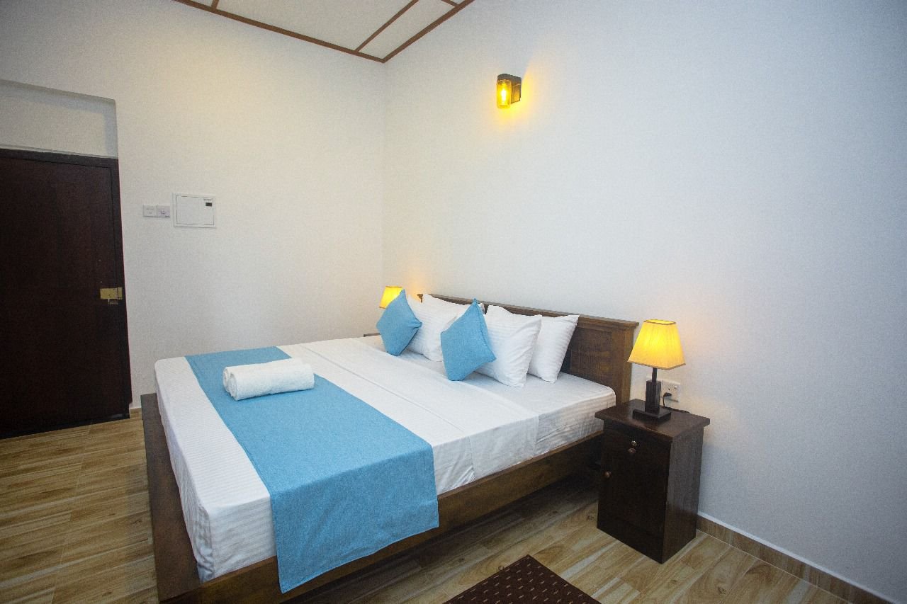 A Deluxe Double Room at Echoing Dream Resort, with a wooden bed frame, bedside lamps and cool linens